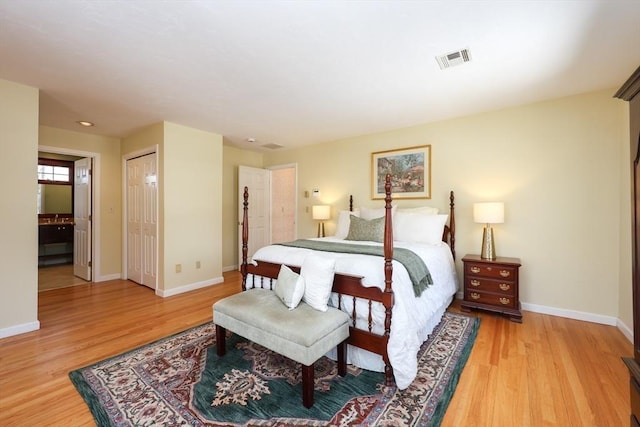 bedroom featuring visible vents, baseboards, ensuite bath, and light wood-style flooring