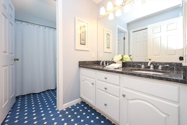 bathroom with a sink, baseboards, and double vanity