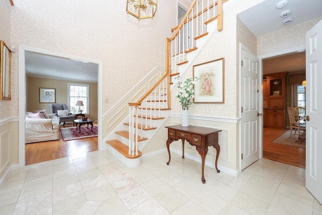 stairs featuring a decorative wall, wainscoting, wallpapered walls, and crown molding