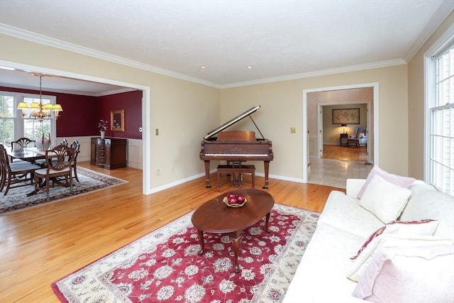 living area with a notable chandelier, wood finished floors, baseboards, and ornamental molding