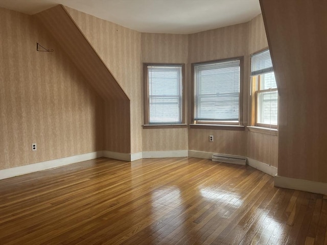 additional living space featuring wood-type flooring, visible vents, baseboards, and wallpapered walls