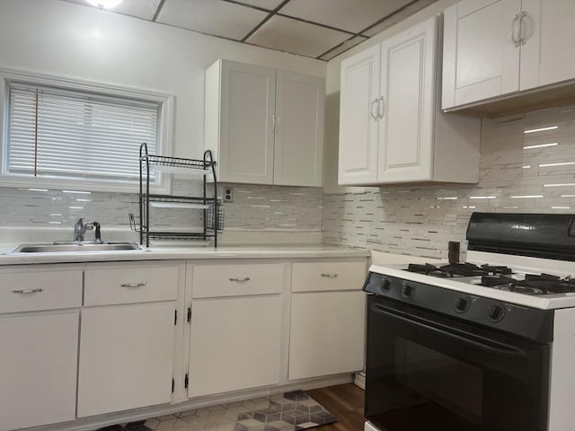 kitchen with white cabinetry, a sink, backsplash, and gas range