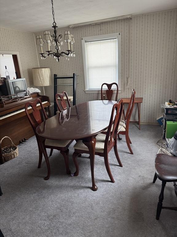 carpeted dining room featuring a notable chandelier