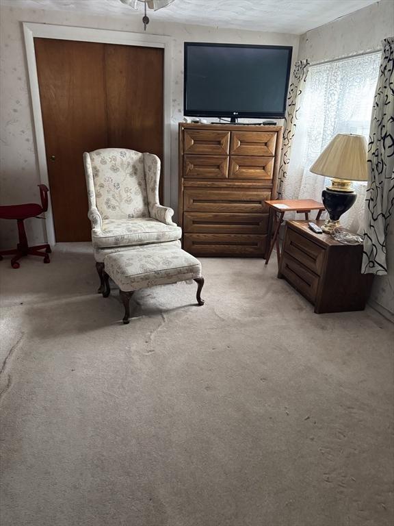 living area with light carpet and a textured ceiling