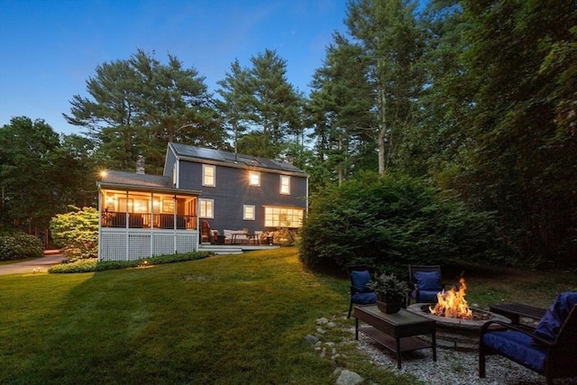 141 Morse Rd, Sudbury, MA 01776 - back of property with an outdoor fire pit, a sunroom, a lawn, and a chimney