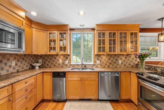 141 Morse Rd, Sudbury, MA 01776 - kitchen featuring appliances with stainless steel finishes, light wood-style flooring, tasteful backsplash, light stone countertops, and glass insert cabinets
