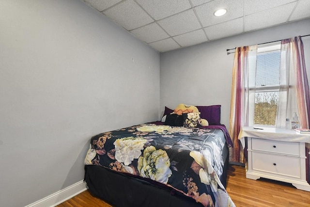 bedroom featuring a paneled ceiling and light wood-type flooring