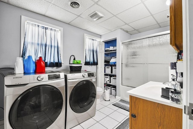 laundry area featuring washer and clothes dryer, sink, and light tile patterned floors