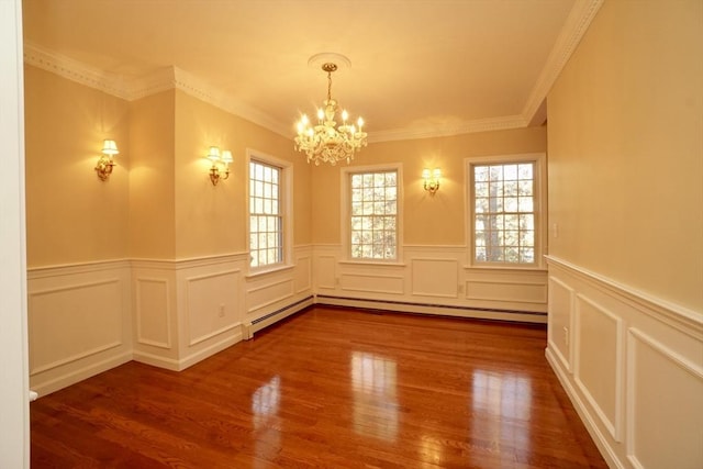 spare room featuring hardwood / wood-style floors, an inviting chandelier, crown molding, and a baseboard heating unit