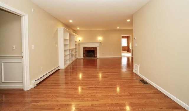 hallway featuring light wood-type flooring, built in features, and a baseboard radiator