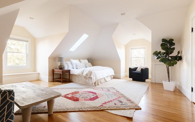 bedroom featuring light hardwood / wood-style floors and vaulted ceiling with skylight