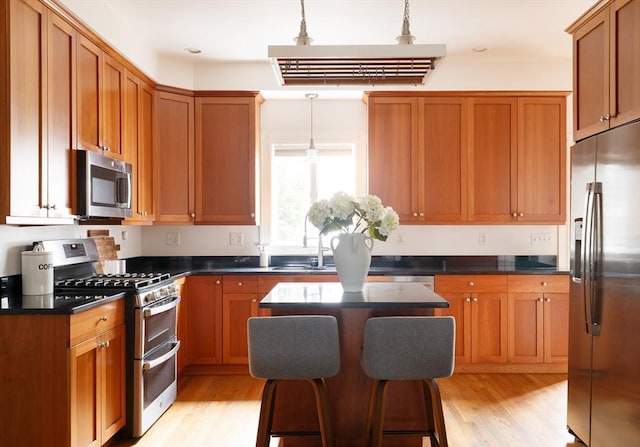 kitchen featuring pendant lighting, a center island, a breakfast bar area, light wood-type flooring, and stainless steel appliances