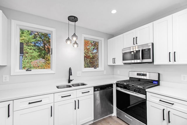 kitchen featuring white cabinetry, hanging light fixtures, stainless steel appliances, and sink