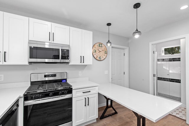 kitchen with light hardwood / wood-style flooring, white cabinets, stainless steel appliances, and pendant lighting