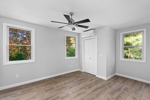 unfurnished room featuring hardwood / wood-style flooring, an AC wall unit, plenty of natural light, and ceiling fan