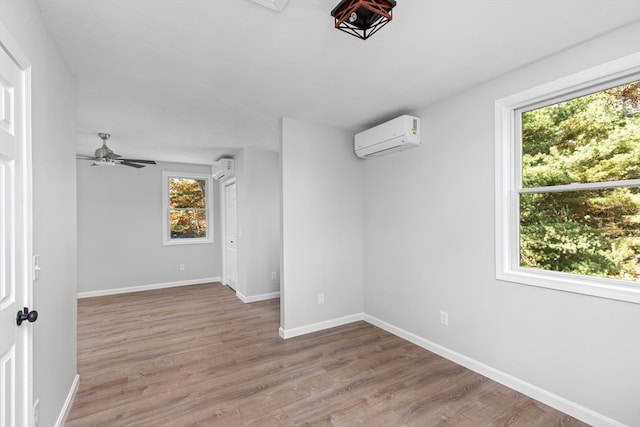 empty room featuring ceiling fan, hardwood / wood-style flooring, and a wall unit AC