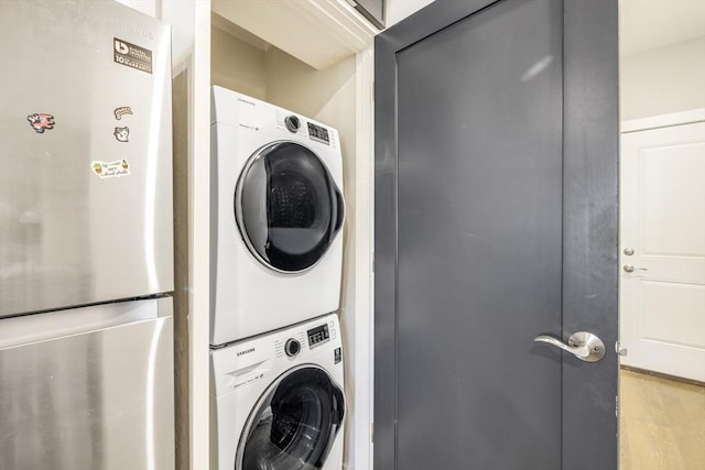 washroom featuring light hardwood / wood-style floors and stacked washing maching and dryer