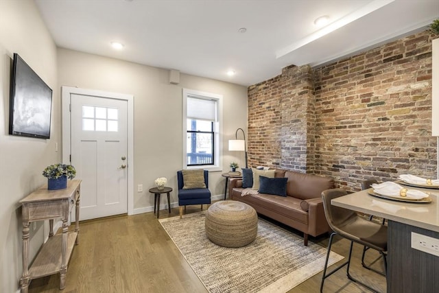 living area with hardwood / wood-style flooring and brick wall