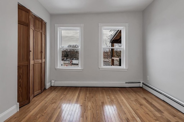 unfurnished room featuring light hardwood / wood-style flooring and a baseboard heating unit