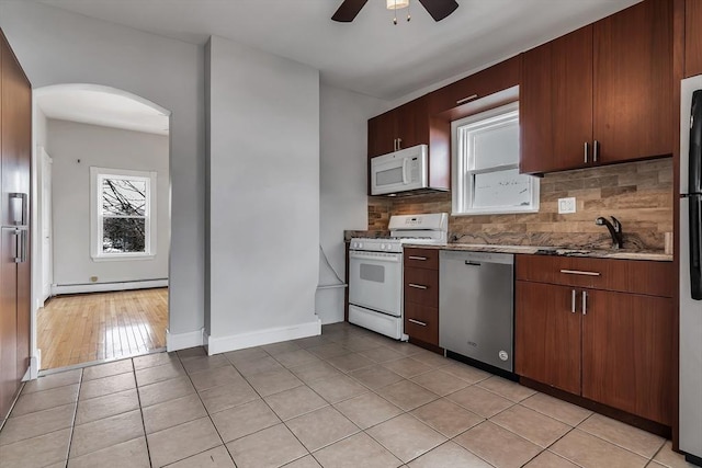 kitchen with a baseboard radiator, white appliances, decorative backsplash, ceiling fan, and light tile patterned floors