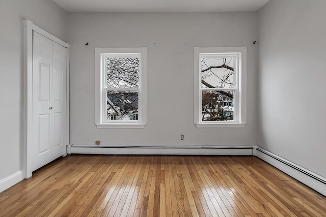 spare room featuring a baseboard heating unit and light hardwood / wood-style flooring