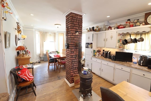 kitchen with decorative columns, white cabinetry, light wood-type flooring, and crown molding