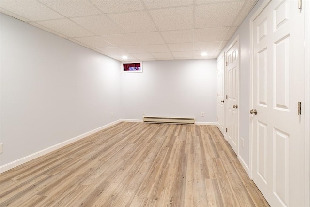 finished below grade area featuring a drop ceiling, light wood-style flooring, baseboards, a baseboard radiator, and recessed lighting