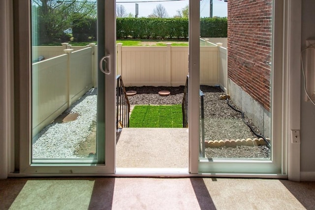 doorway featuring carpet flooring and brick wall