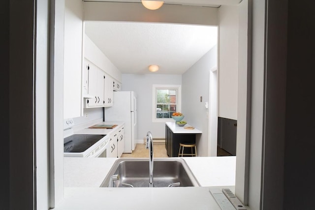 kitchen featuring white cabinets, light countertops, a sink, and white appliances
