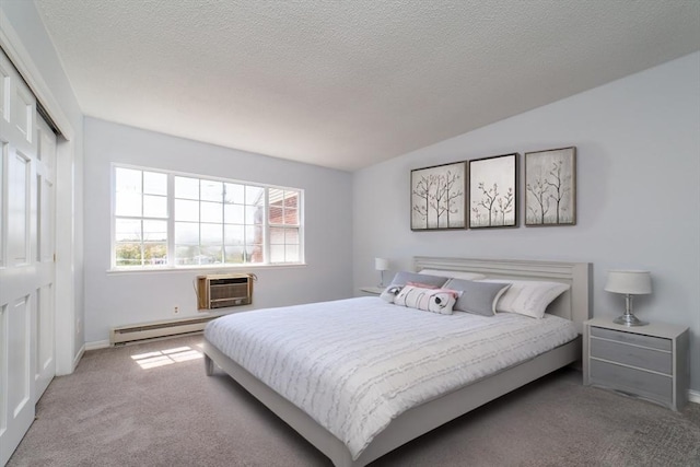 carpeted bedroom featuring a closet, a baseboard heating unit, a textured ceiling, a wall unit AC, and baseboards