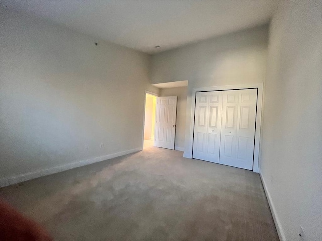 unfurnished bedroom featuring carpet floors, a closet, and a high ceiling