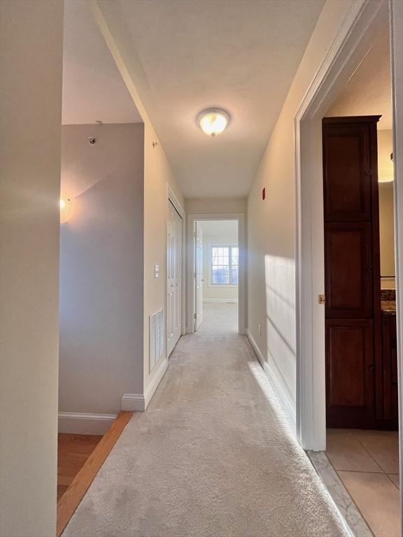 hall with light colored carpet