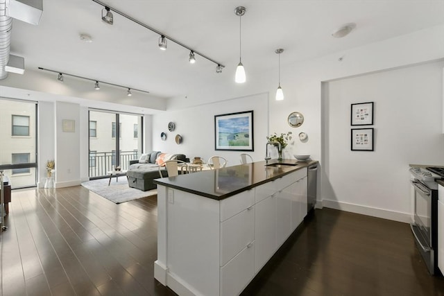 kitchen with white cabinetry, a peninsula, stainless steel appliances, dark countertops, and dark wood-type flooring