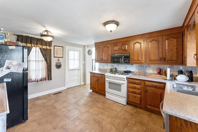 kitchen with white gas range, sink, and backsplash