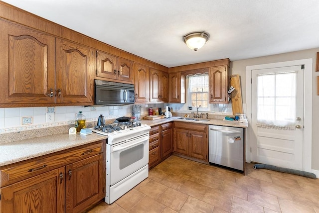 kitchen with sink, gas range gas stove, tasteful backsplash, light stone countertops, and stainless steel dishwasher