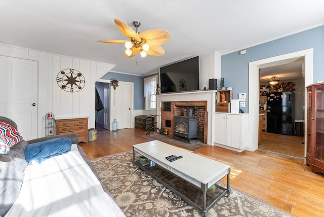 living room featuring crown molding, wood-type flooring, and a wood stove