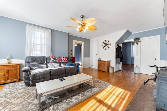 living room with dark hardwood / wood-style flooring, crown molding, and ceiling fan