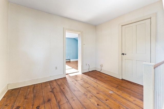 empty room with hardwood / wood-style flooring and baseboard heating