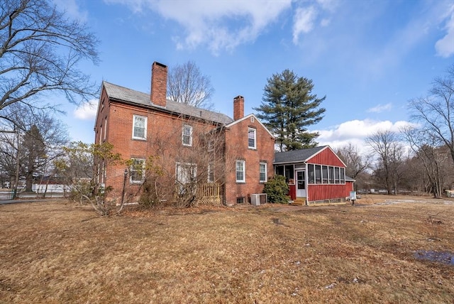 back of property with a yard, a sunroom, and central air condition unit