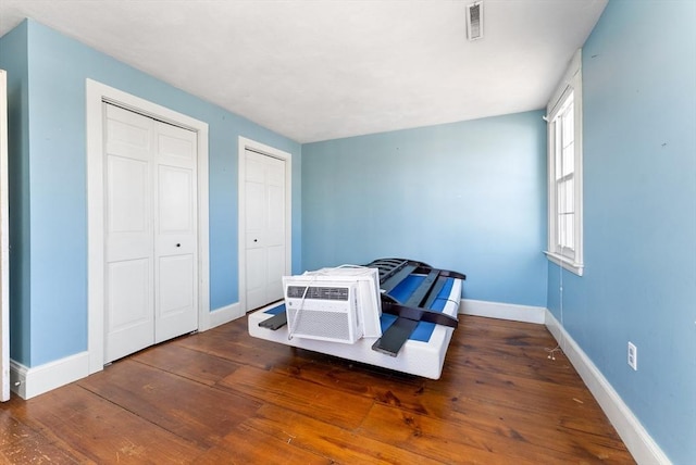 bedroom featuring dark hardwood / wood-style floors and two closets