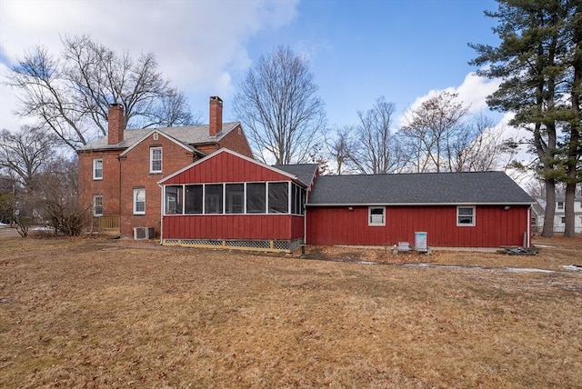 back of house with central air condition unit, a sunroom, and a lawn