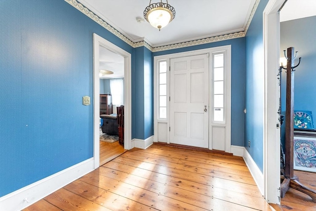 entrance foyer with ornamental molding and light hardwood / wood-style flooring