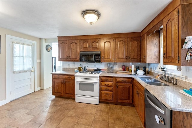 kitchen with dishwasher, sink, backsplash, white gas range oven, and light stone countertops