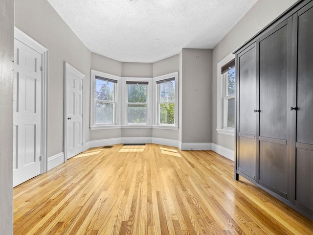 unfurnished bedroom with light hardwood / wood-style floors and a textured ceiling