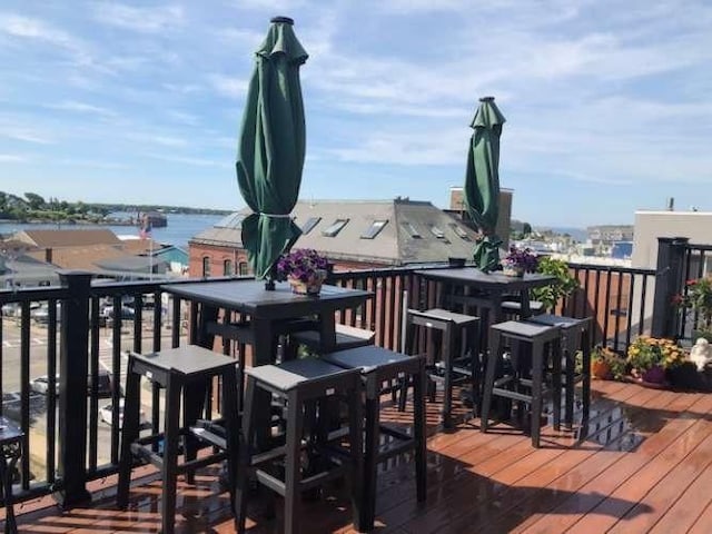 wooden terrace featuring outdoor dining area and a water view
