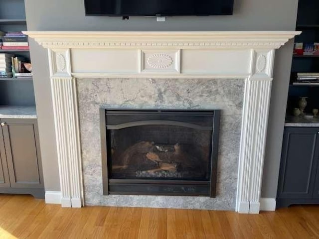detailed view of a high end fireplace, wood finished floors, and baseboards