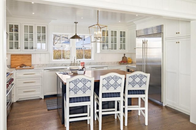 kitchen featuring high quality appliances, white cabinets, ornamental molding, decorative light fixtures, and a kitchen island