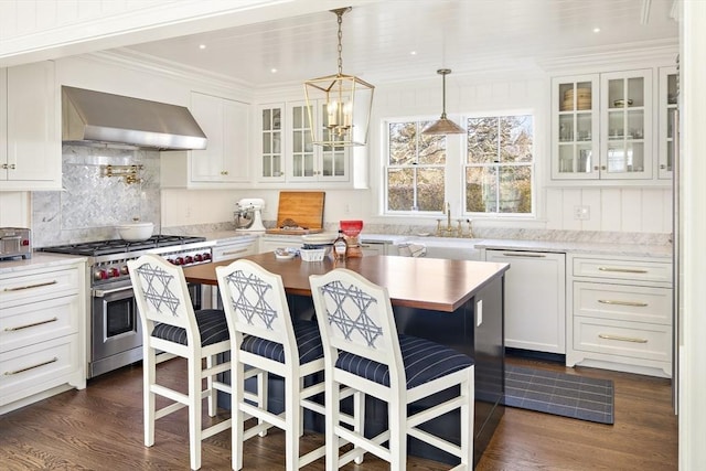 kitchen with wall chimney exhaust hood, stainless steel appliances, white cabinets, a center island, and a breakfast bar area