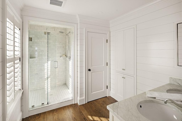 bathroom featuring hardwood / wood-style floors, vanity, a shower with shower door, and crown molding