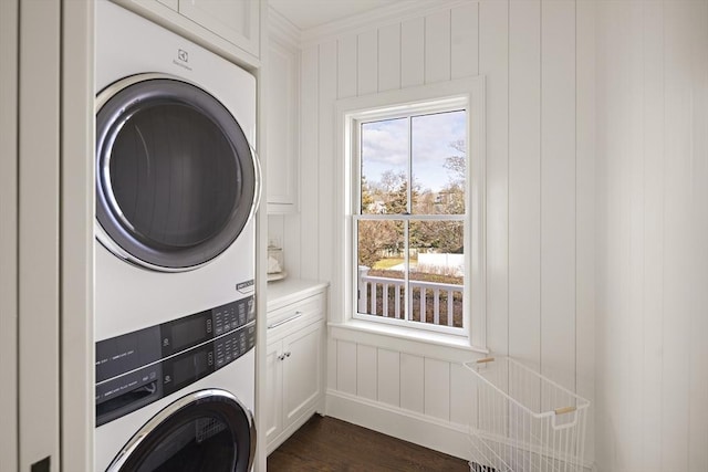 clothes washing area featuring dark hardwood / wood-style floors, cabinets, ornamental molding, and stacked washer and clothes dryer